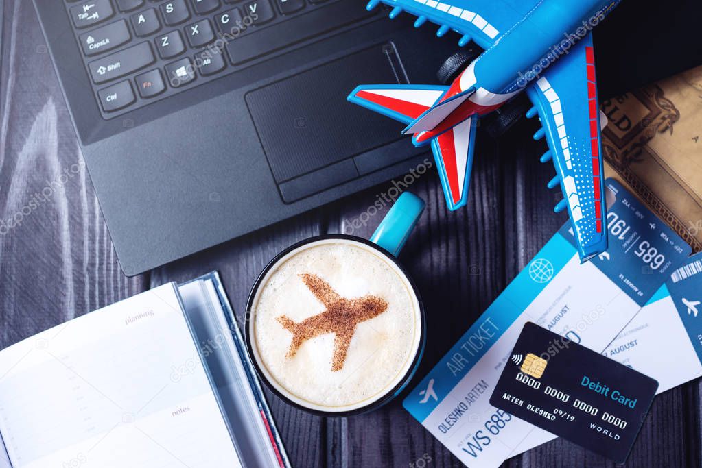 Laptop, plane tickets, coffee, credit card lies on the table