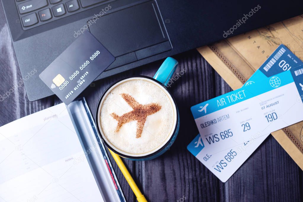 Laptop, plane tickets, coffee, credit card lies on the table