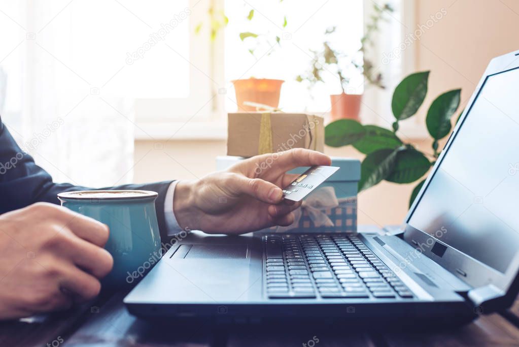 Man working in the office at laptop buying gift online