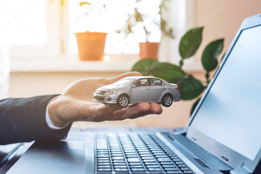 Man in suit working with laptop holding in hands the car. The co