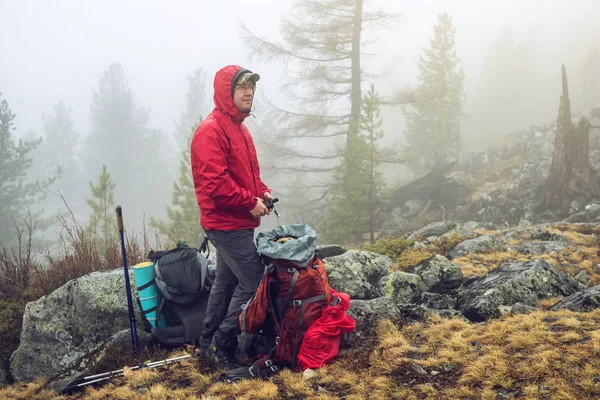 Caminante viaja en el bosque de montaña en la niebla con una mochila. Concepto de viaje y senderismo en lugares salvajes de la naturaleza —  Fotos de Stock