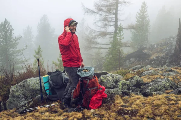 Wanderer ist im Bergwald im Nebel mit Rucksack unterwegs und sucht nach einer mobilen Verbindung — Stockfoto