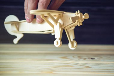 El retro tarzı karanlık bir arka plan üzerinde uçar ahşap oyuncak uçak tutar