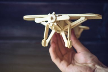 El retro tarzı karanlık bir arka plan üzerinde uçar ahşap oyuncak uçak tutar