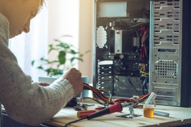 Adam tamirci bir işyeri ofis yeri bilgisayardaki araçları kullanılarak tamir etmeye çalışıyor