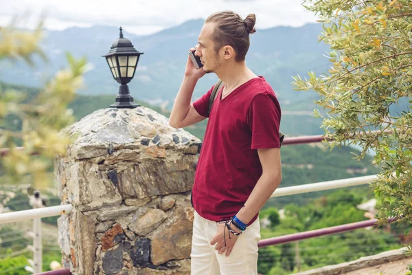 Hombre viajero hablando por teléfono en un fondo de montañas — Foto de Stock