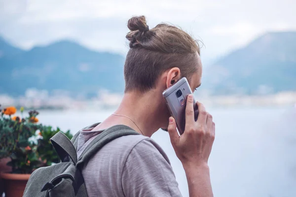 Hombre viajero con mochila hablando por teléfono en el fondo de la ciudad . — Foto de Stock