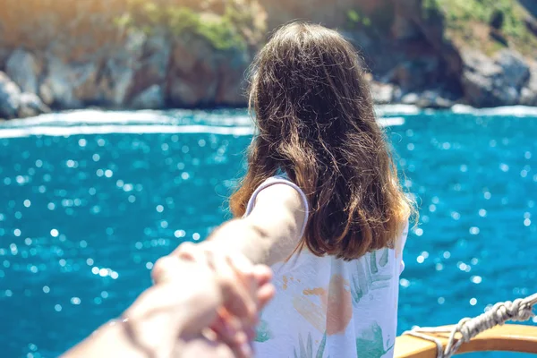 Follow me, Attractive brunette girl holding the hand leads to the mountains and the blue sea