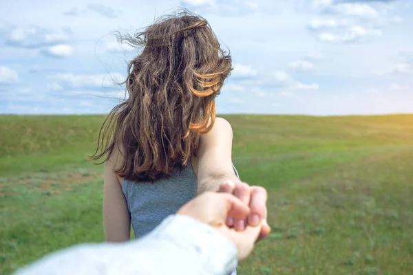 Seguimi, attraente ragazza bruna che tiene per mano i cavi in un campo verde pulito, steppa con le nuvole — Foto Stock
