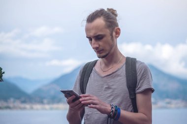 Adam Gezgin ile onun smartphone vasıl doğa ve dağ arka plan üzerinde seyir sırt çantası