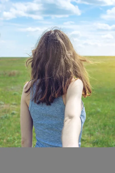 Sígueme, chica morena atractiva sosteniendo la mano de los plomos en un campo verde limpio, estepa con nubes — Foto de Stock