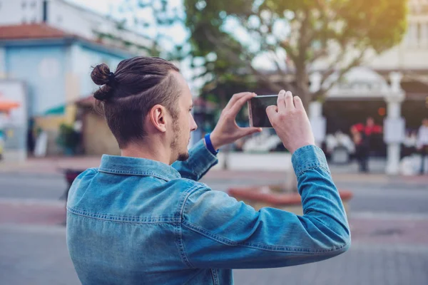 Mochila homem faz uma foto em seu smartphone em uma rua da cidade — Fotografia de Stock