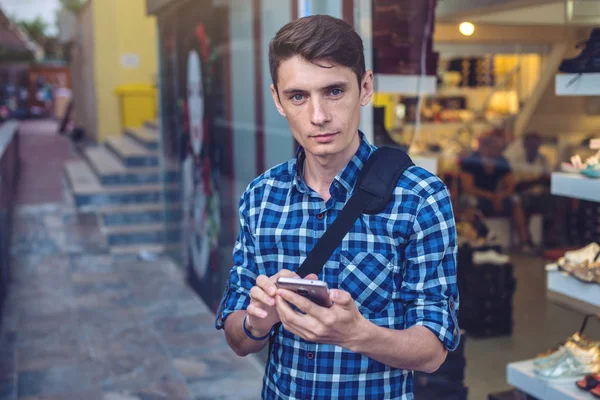 Путешественник смотрит на свой смартфон на фоне улиц города — стоковое фото
