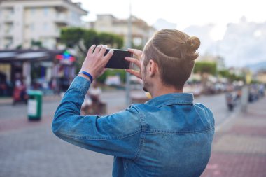 Adam sırt çantası bir fotoğraf üzerinde bir şehir smartphone sokak yapar