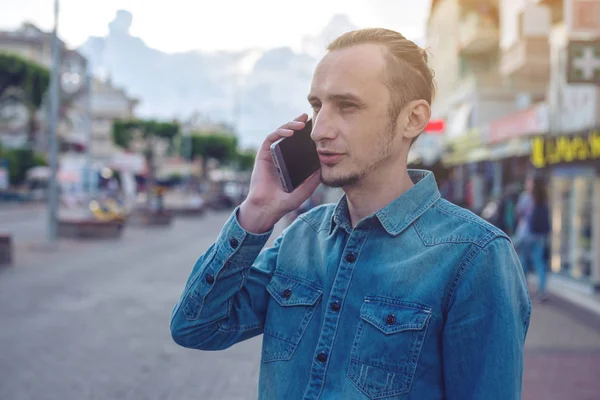 Человек путешественник с рюкзаком разговаривает по телефону на заднем плане улицы . — стоковое фото