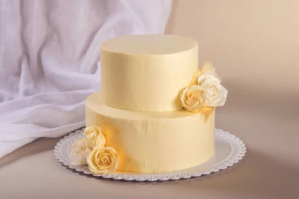 Beige 2 torta nuziale a più livelli decorato con rose mastice stand su sfondo tessuto — Foto Stock