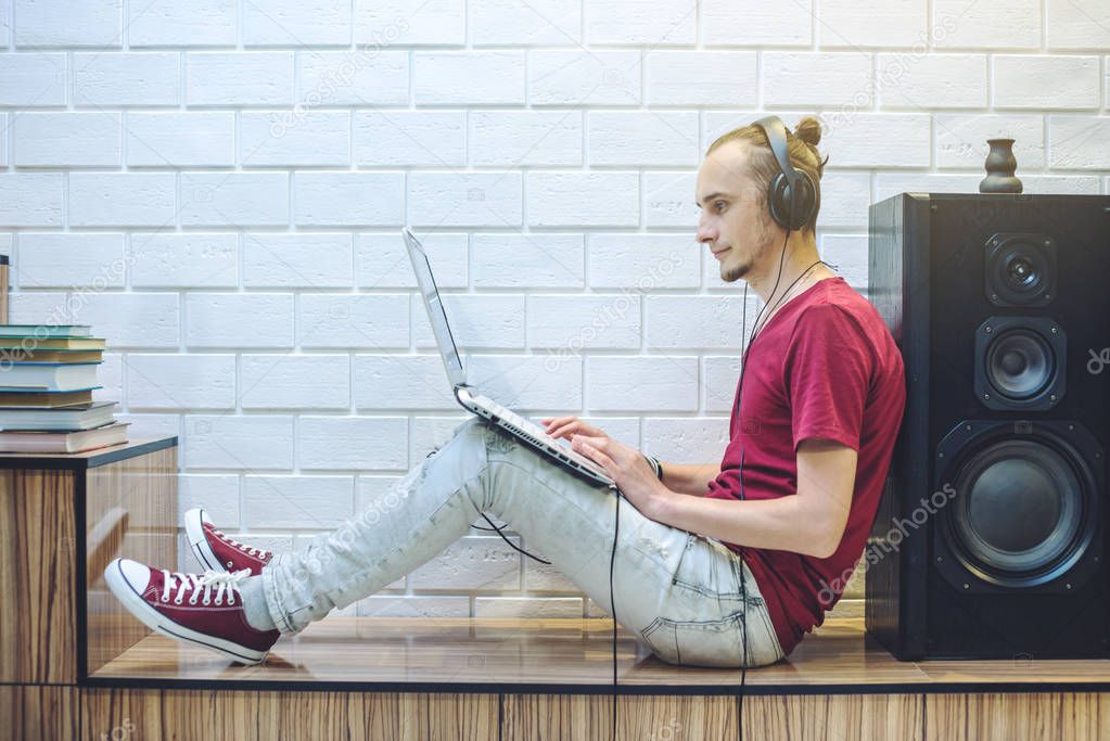 Young man with headphones listening to lessons and working at a laptop. The concept of technology and modern education