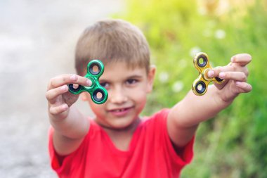 Bir çocuk elini açık havada üzerinde büküm spinner çalış. Çocukların anti-stres oyuncakları eğilimler
