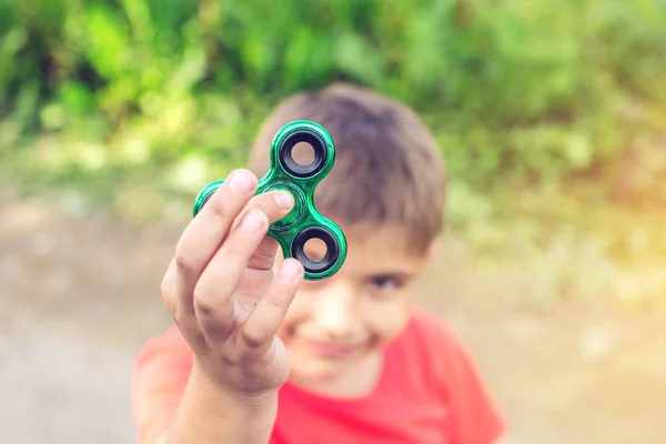 Un garçon joue avec spinner le tordant dans sa main à l'extérieur. Tendances dans les jouets anti-stress pour enfants — Photo