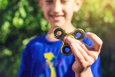 Bir çocuk elini açık havada üzerinde büküm spinner çalış. Çocukların anti-stres oyuncakları eğilimler