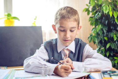 Okula dönüş. Şirin çocuk sınıfta masasında oturuyor. Çocuk dersleri öğreniyor. Kavram İlköğretim Okulu