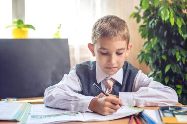 Okula dönüş. Şirin çocuk sınıfta masasında oturuyor. Çocuk dersleri öğreniyor. Kavram İlköğretim Okulu