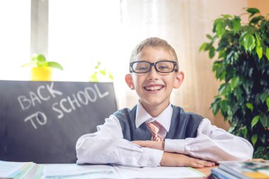 Okula dönüş. Şirin çocuk sınıfta masasında oturuyor. Çocuk dersleri öğreniyor. Kavram İlköğretim Okulu