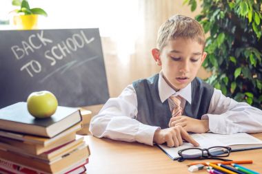 Okula dönüş. Şirin çocuk sınıfta masasında oturuyor. Çocuk dersleri öğreniyor. Kavram İlköğretim Okulu