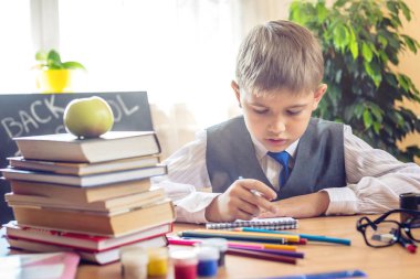 Okula dönüş. Şirin çocuk sınıfta masasında oturuyor. Çocuk dersleri öğreniyor. Kavram İlköğretim Okulu