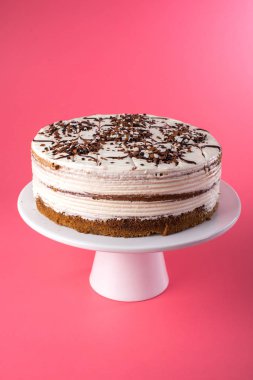 Rustik tarzı pembe bir arka plan üzerinde beyaz krema ile izole ev yapımı katmanlı sünger kek