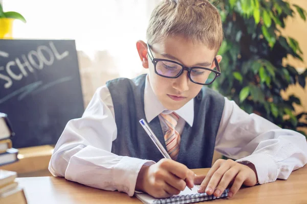 Zurück zur Schule. Nettes Kind, das am Schreibtisch im Klassenzimmer sitzt. Junge zieht Lehren. Konzept Grundschule — Stockfoto