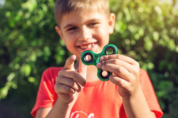 Bir çocuk elini açık havada üzerinde büküm spinner çalış. Çocukların anti-stres oyuncakları eğilimler