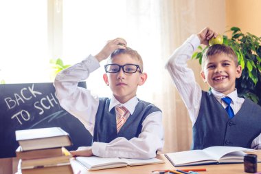 Okula dönüş. Şirin çocuk sınıfta masasında oturuyor. Çocuklar çok yaramazsın ve kafasına elma tutun