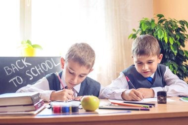 Okula dönüş. Şirin çocuk sınıfta masasında oturuyor. Çocuklar ders öğrenme. Kavram İlköğretim Okulu