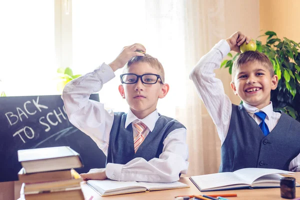 Okula dönüş. Şirin çocuk sınıfta masasında oturuyor. Çocuklar çok yaramazsın ve kafasına elma tutun