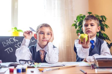 Okula dönüş. Şirin çocuk sınıfta masasında oturuyor. Çocuklar hareket bir kağıt uçak kusuyor.