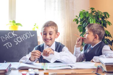 Okula dönüş. Şirin çocuk sınıfta masasında oturuyor. Yaramaz çocuklar