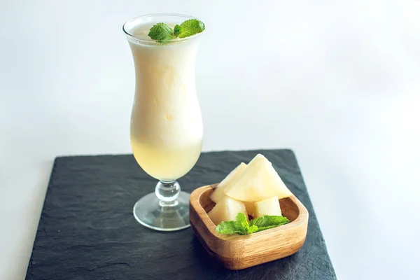 Čerstvý bílý smoothie ve sklenici s nakrájené kousky melounu a máty na bílém pozadí izolované. Letní studené nápoje — Stock fotografie
