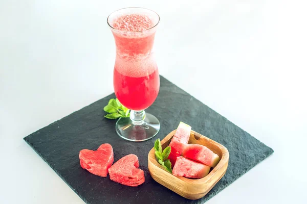 Batido rojo fresco en un vaso con trozos de sandía en rodajas y menta sobre fondo blanco aislado. Bebidas frescas de verano — Foto de Stock