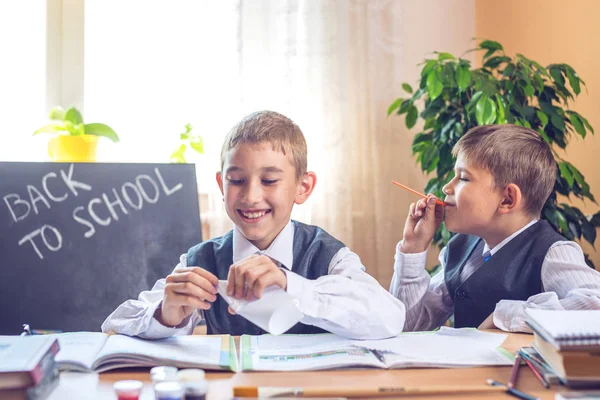 学校に戻る教室で机に座っているかわいい子供たち。男の子がいたずら — ストック写真