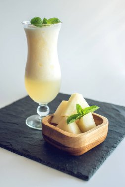 Kavun ve beyaz izole zemin üzerine nane dilimlenmiş parçaları ile bir bardak taze beyaz yüzlü. Yaz soğuk içecekler
