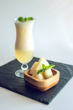 Kavun ve beyaz izole zemin üzerine nane dilimlenmiş parçaları ile bir bardak taze beyaz yüzlü. Yaz soğuk içecekler