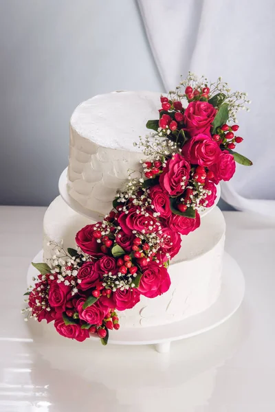 Una gran torta de boda estratificada decorada con rosas rojas sobre la mesa —  Fotos de Stock