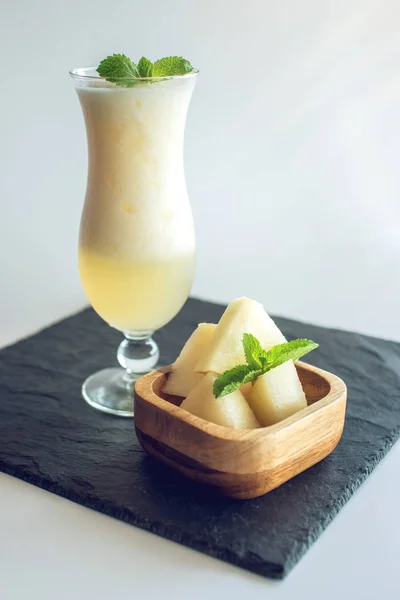 Čerstvý bílý smoothie ve sklenici s nakrájené kousky melounu a máty na bílém pozadí izolované. Letní studené nápoje — Stock fotografie