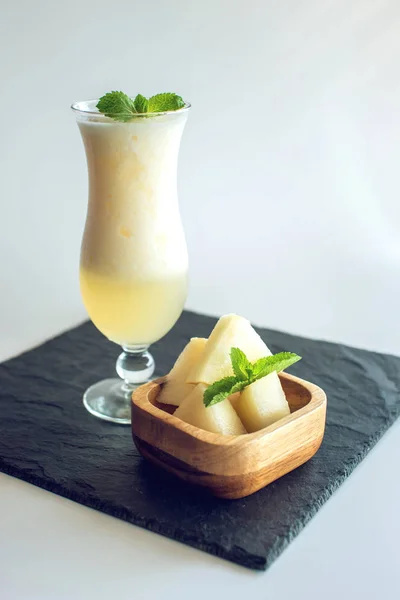 Fresh white smoothie in a glass with sliced pieces of melon and mint on white isolated background. Summer cool drinks — Stock Photo, Image