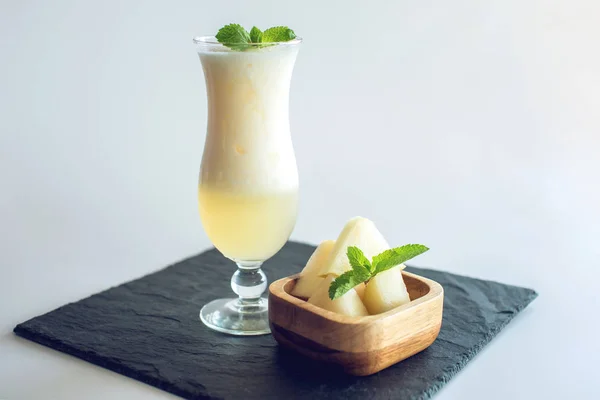 Batido blanco fresco en un vaso con trozos de melón en rodajas y menta sobre fondo blanco aislado. Bebidas frescas de verano — Foto de Stock