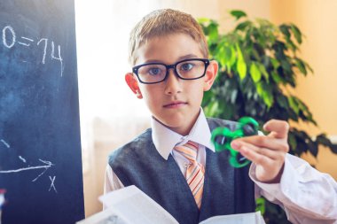 Okula dönüş. Şirin çocuk sınıfta masasında oturuyor. Ders sırasında bir spinner ile oynayan çocuk