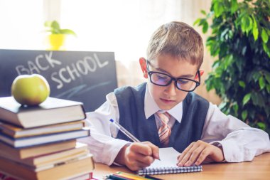 Okula dönüş. Şirin çocuk sınıfta masasında oturuyor. Çocuk dersleri öğreniyor. Kavram İlköğretim Okulu