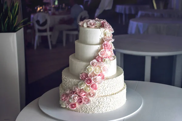 Duże warstwowych tort weselny z róż na stole w restauracji — Zdjęcie stockowe