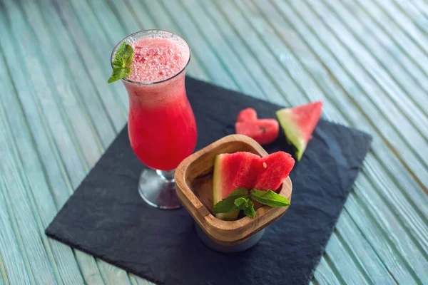 Čerstvé červené smoothie ve sklenici s nakrájené kousky melounu a máty na modrém pozadí dřevěná. Letní studené nápoje — Stock fotografie